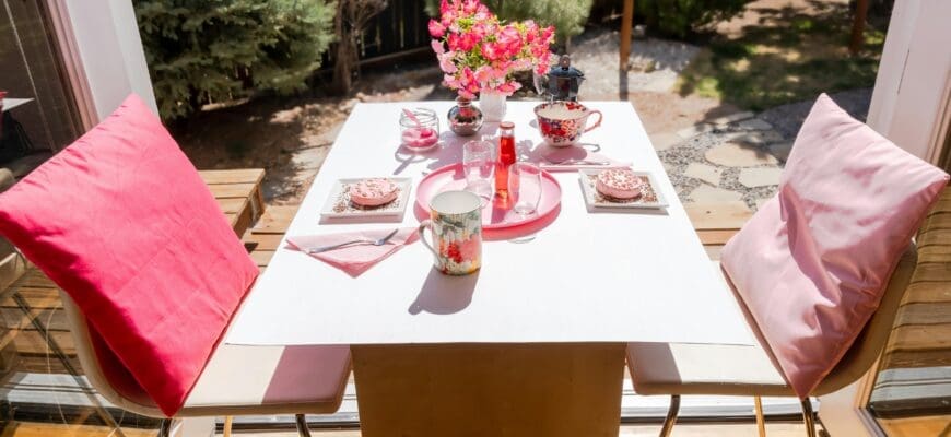 A Patio Table Set with Plates, Cups, and a Vase with Flowers